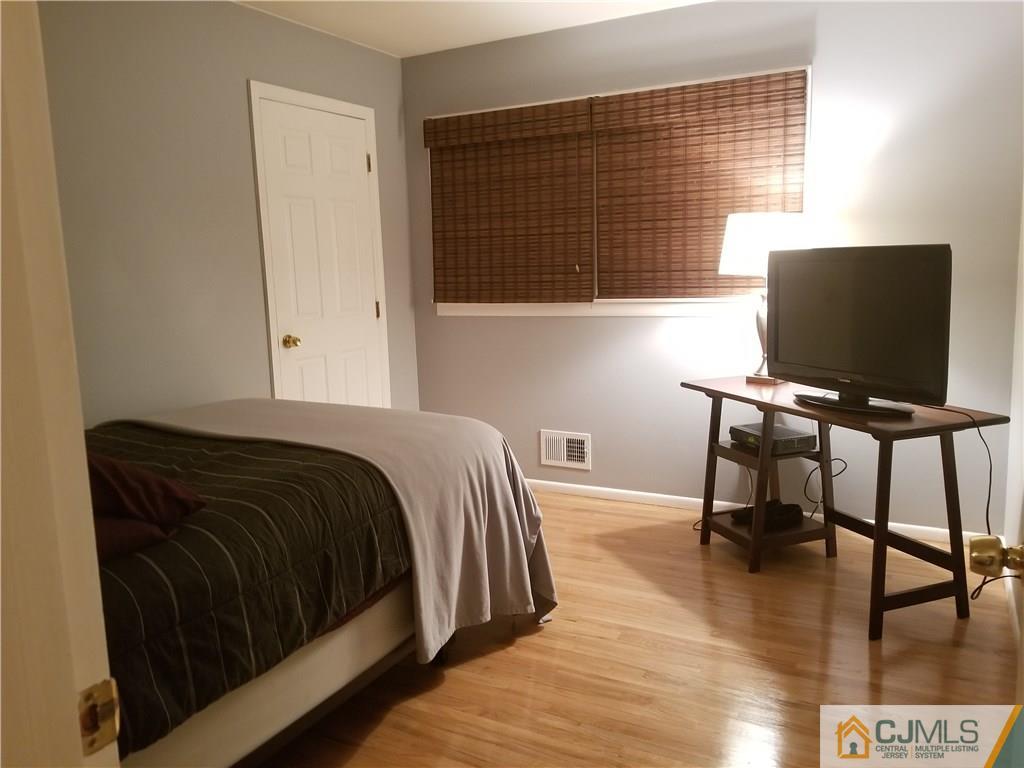 47 Harmon Road Edison, NJ 08837 - Photo 16 of 24 a bedroom with a bed and a flat tv screen on the dresser