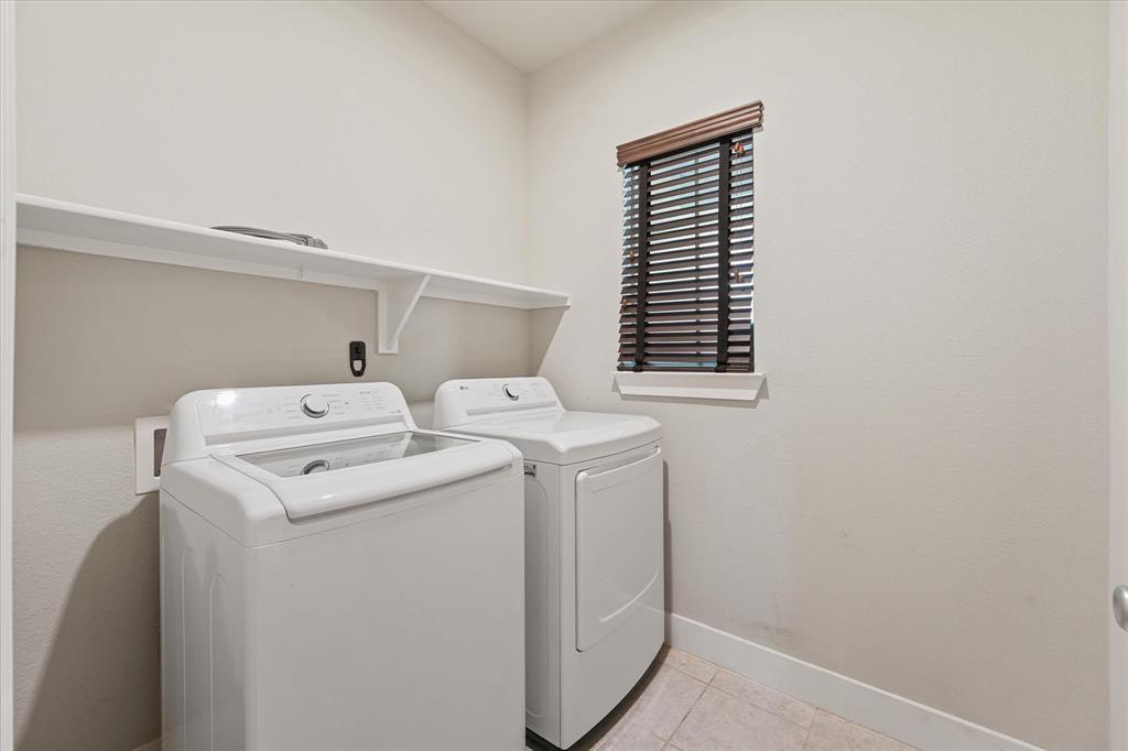 2044 Longbridge Road Forney, TX 75126 - Photo 11 of 40 Functional laundry area featuring a window with dark wood-finish blinds, a built-in white shelf, and tiled flooring