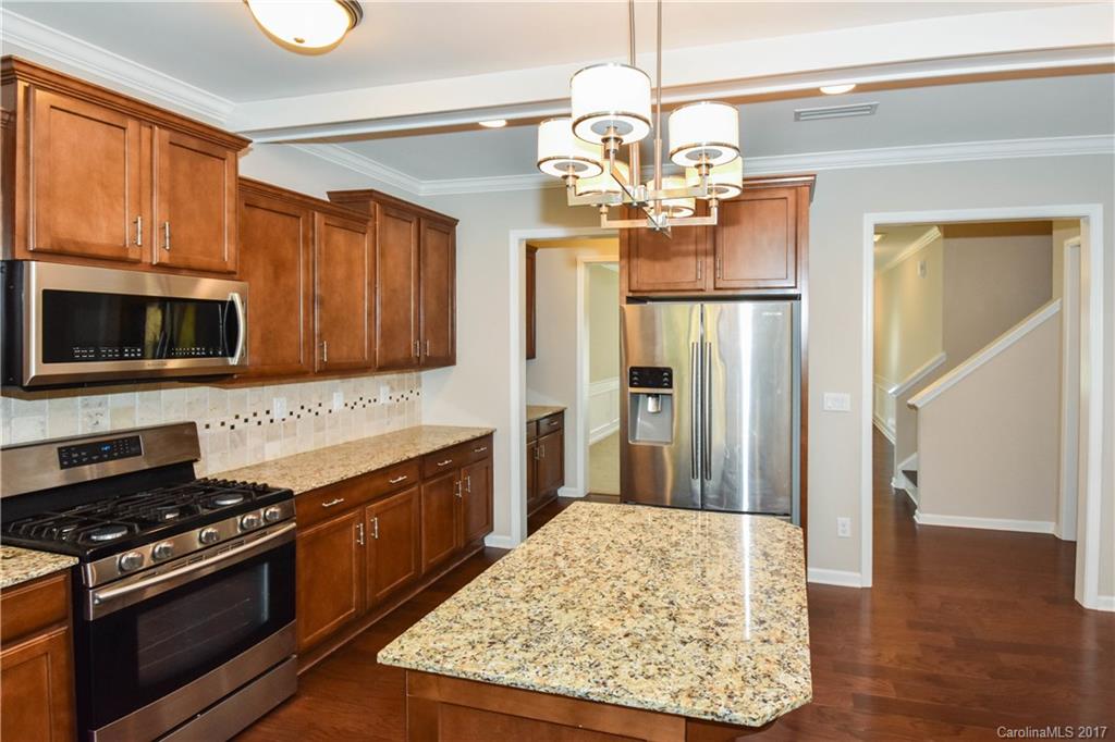 7079 Meyer Road Fort Mill, SC 29715 - Photo 5 of 20 a kitchen with stainless steel appliances granite countertop a stove top oven a refrigerator and a sink with wooden floor