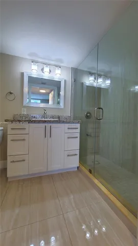a bathroom with a granite countertop sink a mirror and a shower