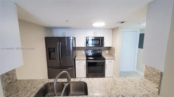 a kitchen with stainless steel appliances granite countertop a refrigerator and a sink