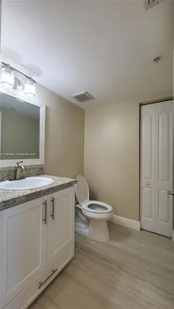 a bathroom with a granite countertop toilet sink and mirror
