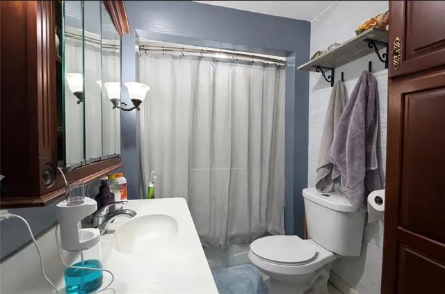 a bathroom with a sink a toilet a mirror and shower curtain