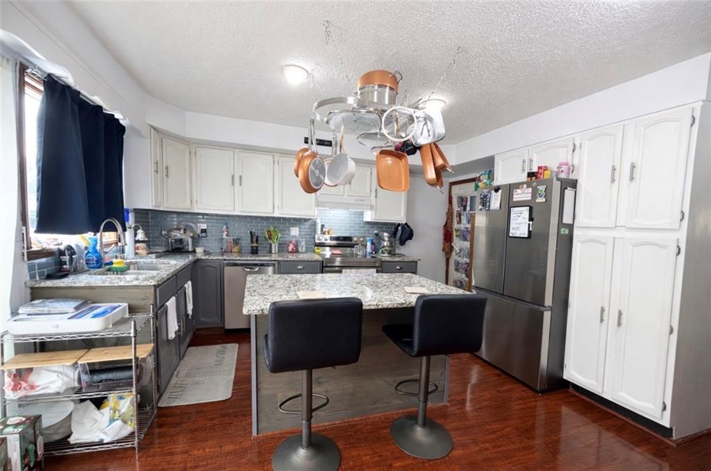 329 New Castle Street Slippery Rock, PA 16057 - Photo 5 of 27 a kitchen with stainless steel appliances granite countertop a refrigerator a stove a sink dishwasher and a dining table with wooden floor