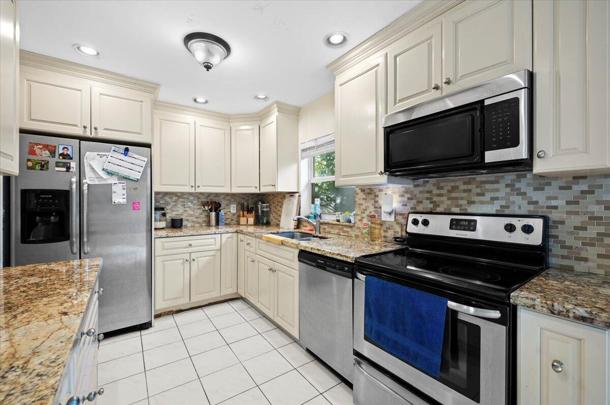 19309 Carolina Circle Boca Raton, FL 33434 - Photo 13 of 30 a kitchen with stainless steel appliances granite countertop a stove top oven a sink dishwasher a refrigerator and a microwave
