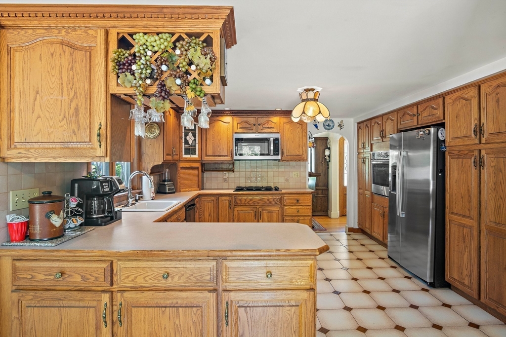 4 Merrow Lane Stoneham, MA 02180 - Photo 4 of 33 a kitchen with a sink a refrigerator and cabinets