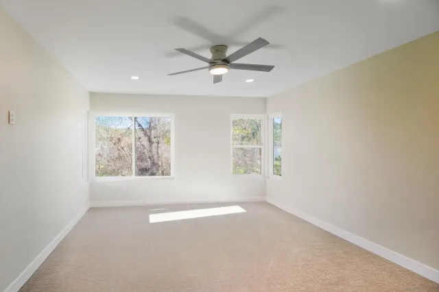 an empty room with windows and ceiling fan