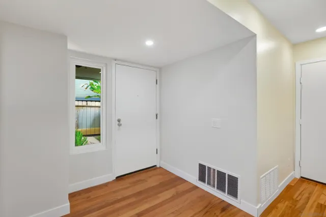 a view of an empty room with window and wooden floor