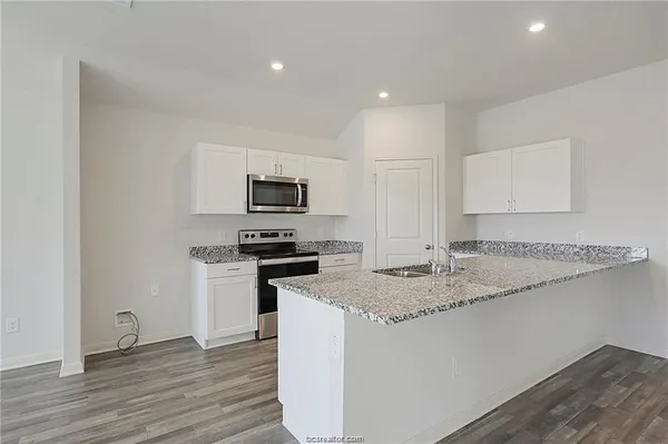 a kitchen with a sink a stove a microwave and wooden floor