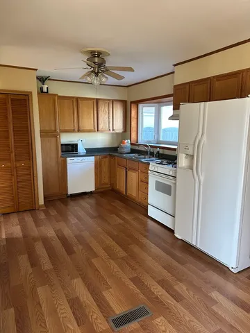 a kitchen with a refrigerator wooden floor a sink and a stove