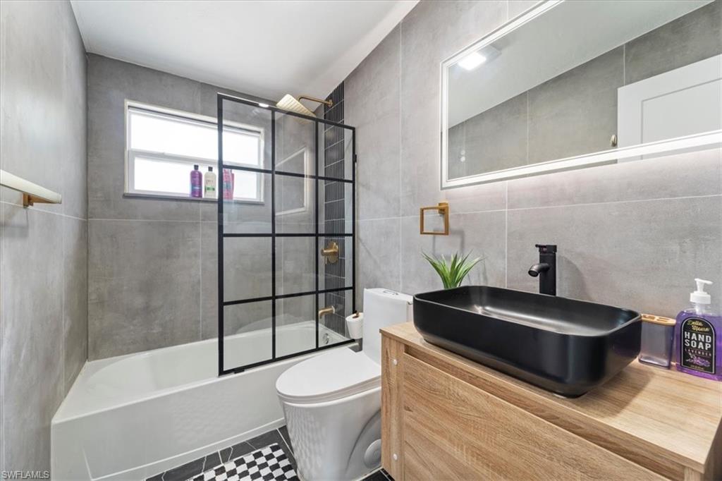 2123 Holiday Lane Naples, FL 34104 - Photo 13 of 32 Full bathroom featuring tile patterned flooring, toilet, shower / bath combination with glass door, vanity, and tile walls