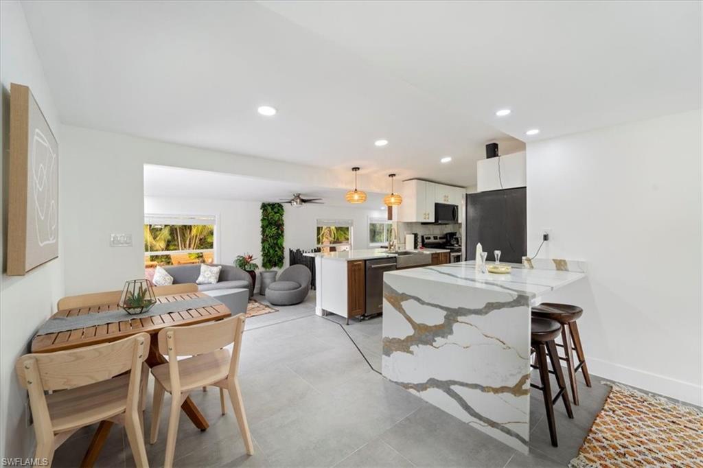 2123 Holiday Lane Naples, FL 34104 - Photo 14 of 32 Kitchen featuring pendant lighting, a breakfast bar, white cabinets, appliances with stainless steel finishes, and kitchen peninsula
