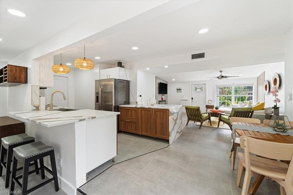 2123 Holiday Lane Naples, FL 34104 - Photo 6 of 32 Kitchen with kitchen peninsula, stainless steel fridge, ceiling fan, sink, and hanging light fixtures