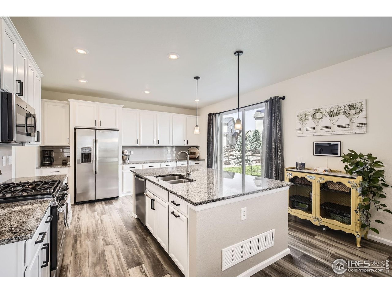 12889 Clearview Street Firestone, CO 80504 - Photo 4 of 38 a open kitchen with stainless steel appliances granite countertop a stove top oven a refrigerator a sink and a dining table with wooden floor