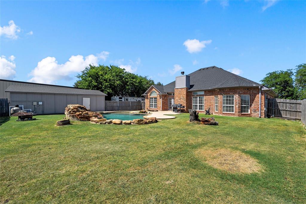 3696 Old Lorena Road Lorena, TX 76655 - Photo 25 of 27 Expansive backyard featuring a sparkling in-ground pool with rock detailing, a concrete patio, and a large detached outbuilding