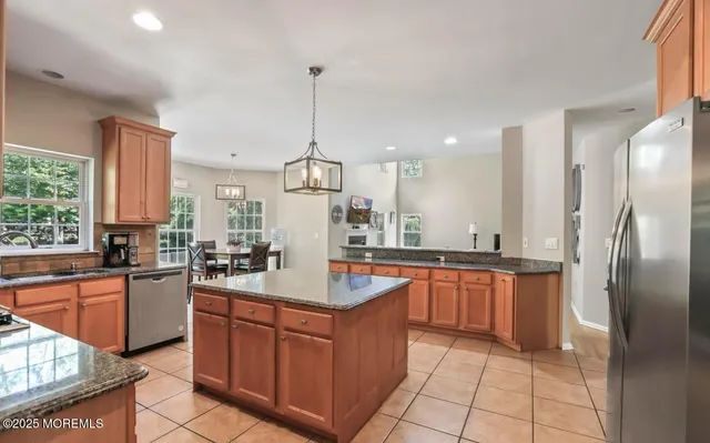a kitchen with stainless steel appliances granite countertop a sink a refrigerator and center island