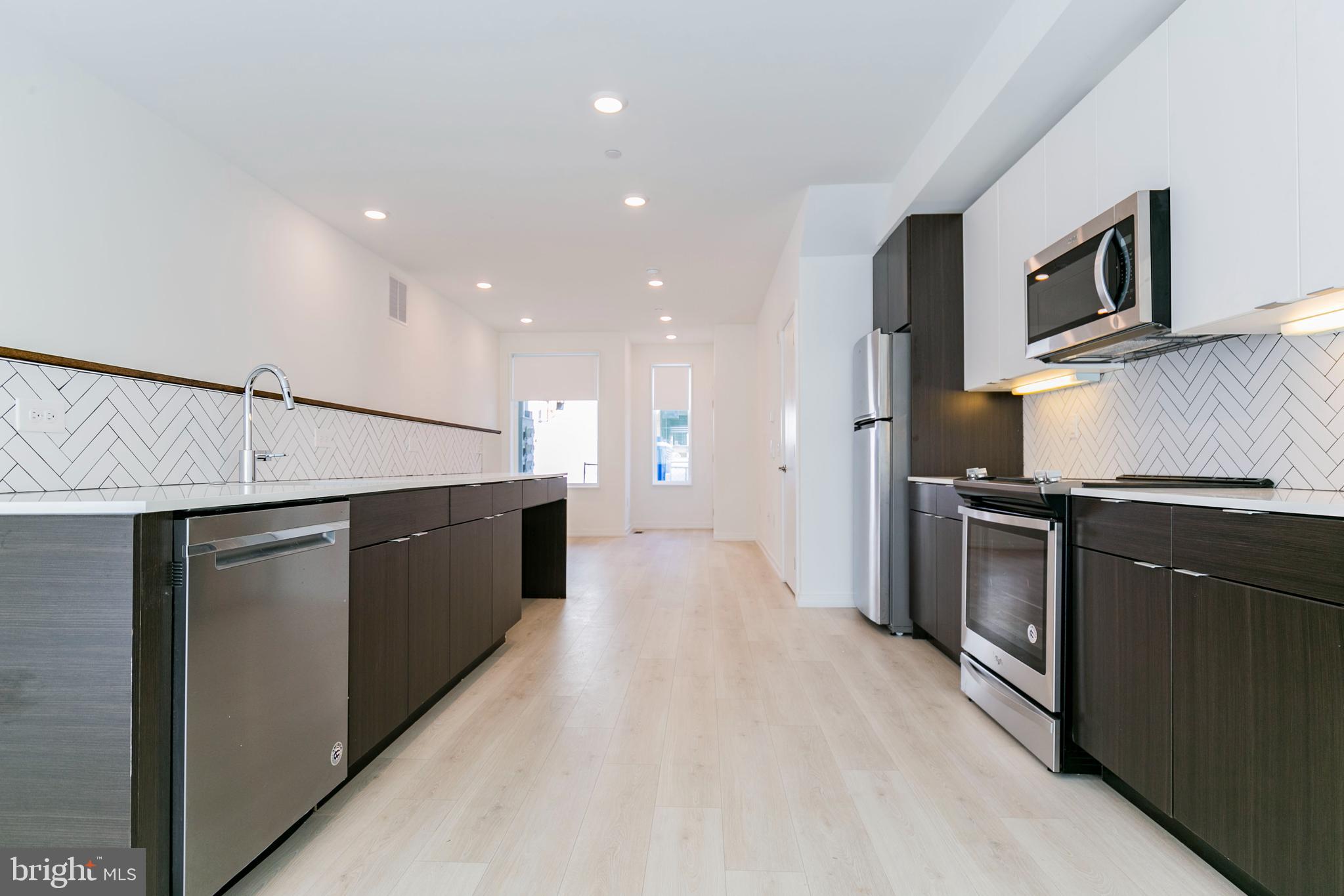 a large kitchen with stainless steel appliances kitchen island granite countertop a refrigerator a stove top oven and a sink