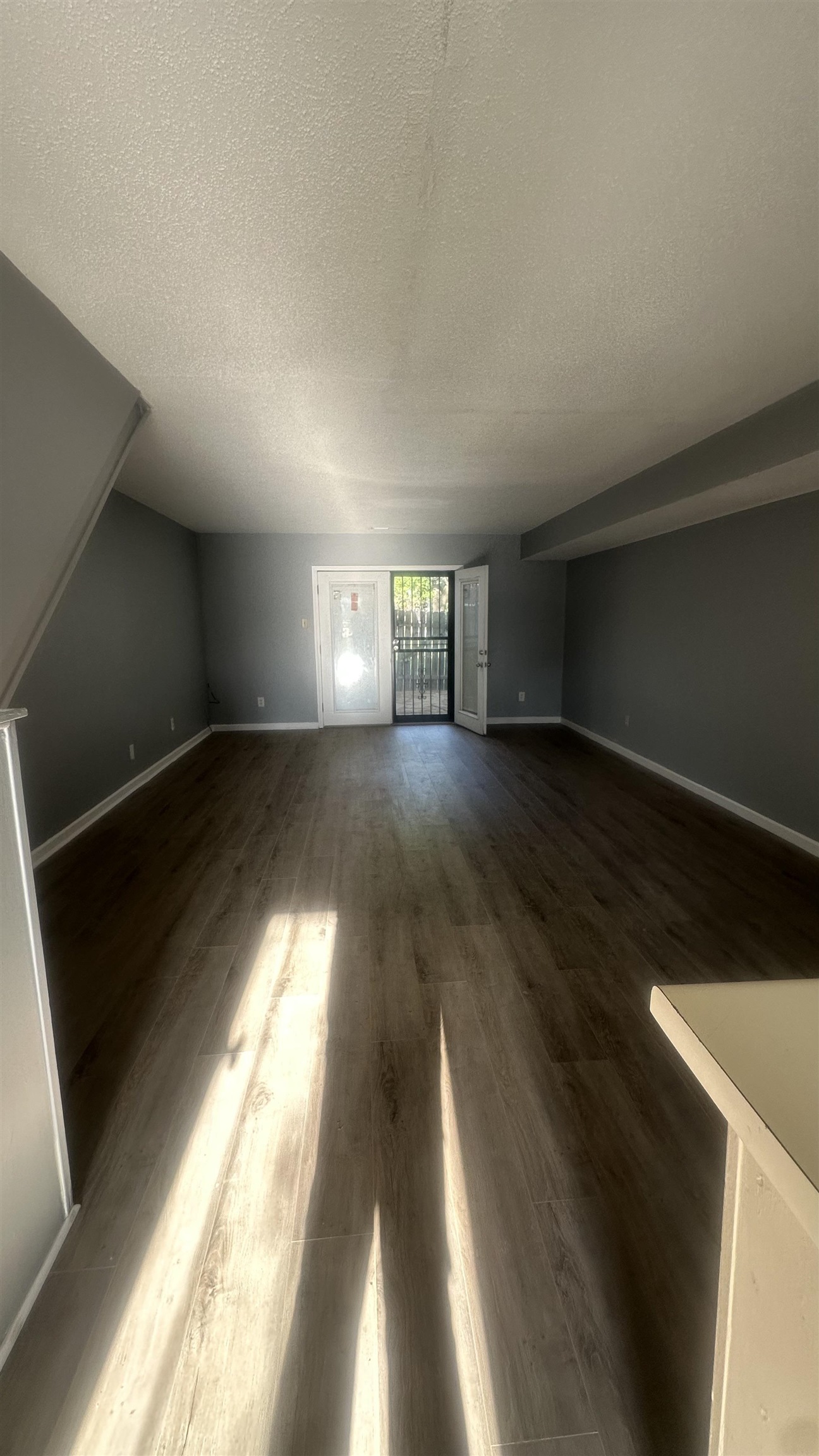 3811 South Mendenhall Road, Unit 3811 Memphis, TN 38115 - Photo 16 of 18 Unfurnished living room with dark wood finished floors, baseboards, a textured ceiling, and lofted ceiling