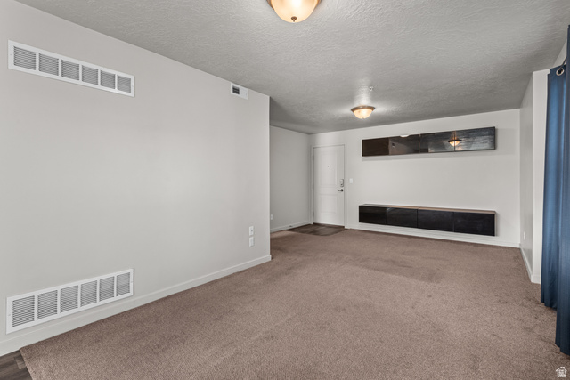 1700 South Sandhill Road West, Unit E 301 Orem, UT 84058 - Photo 4 of 20 Spacious living area featuring neutral carpeting, a white entry door, and overhead dome lighting fixtures