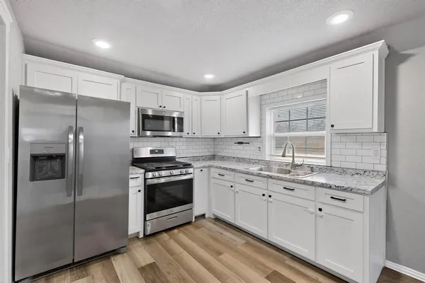 a kitchen with stainless steel appliances granite countertop a stove a sink and a refrigerator