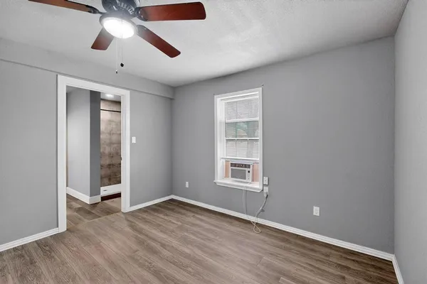an empty room with wooden floor chandelier fan and windows