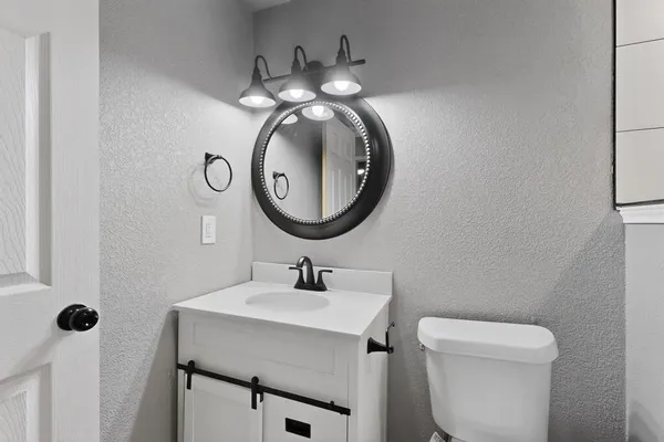 a bathroom with a toilet sink vanity and mirror