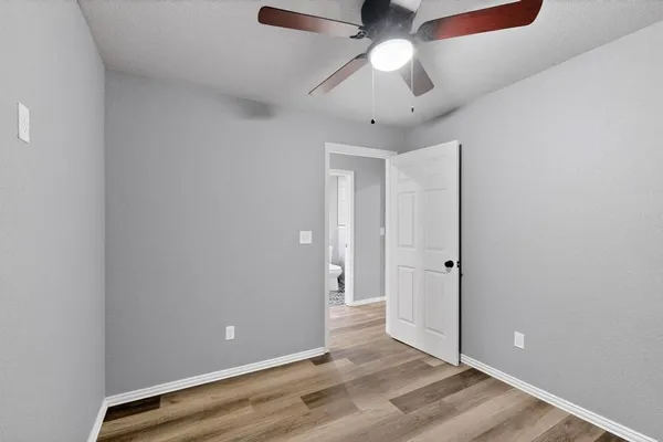 an empty room with wooden floor and ceiling fan