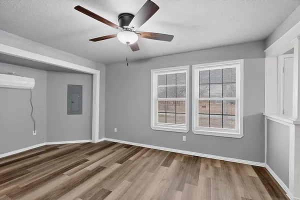 an empty room with wooden floor and windows