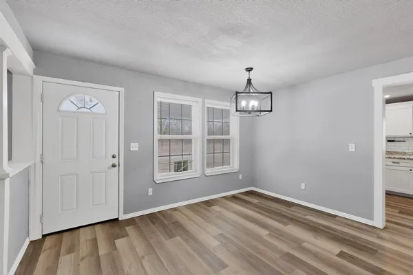 an empty room with wooden floor cabinet and windows
