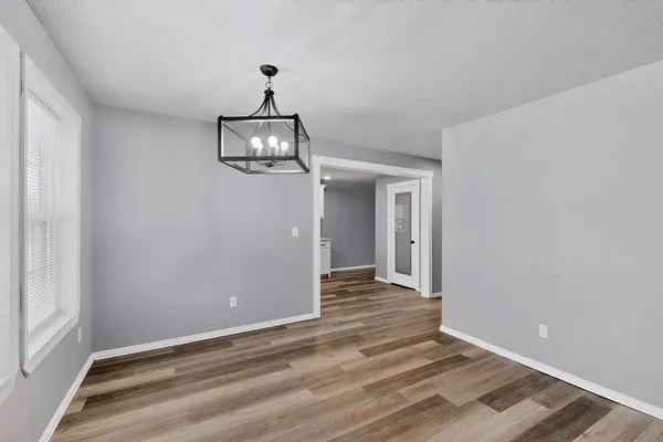 a view of a hallway with wooden floor and chandelier