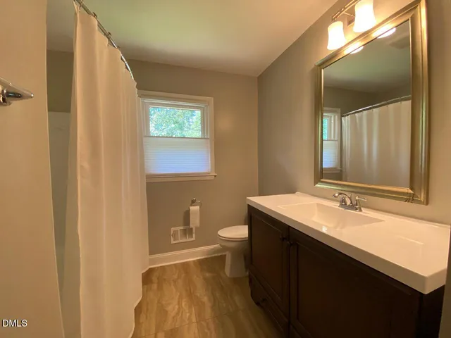 a bathroom with a granite countertop sink toilet and mirror