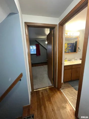 a view of a hallway and a livingroom with wooden floor and a bathroom