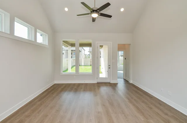 a view of an empty room with window and wooden floor