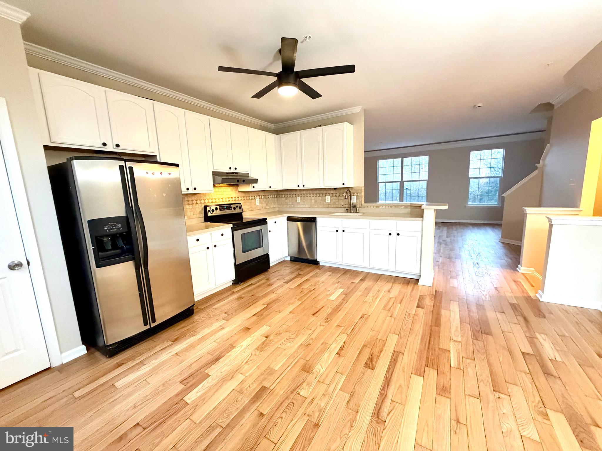 10158 Tree Frog Place White Plains, MD 20695 - Photo 10 of 25 a large kitchen with a refrigerator a sink dishwasher a stove and white cabinets with wooden floor