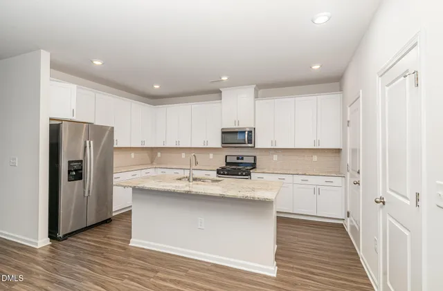 a kitchen with stainless steel appliances granite countertop a refrigerator and a stove top oven