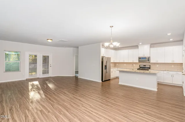 a view of a kitchen with granite countertop wooden floor stainless steel appliances and a fireplace