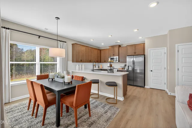 a kitchen with a dining table chairs and refrigerator