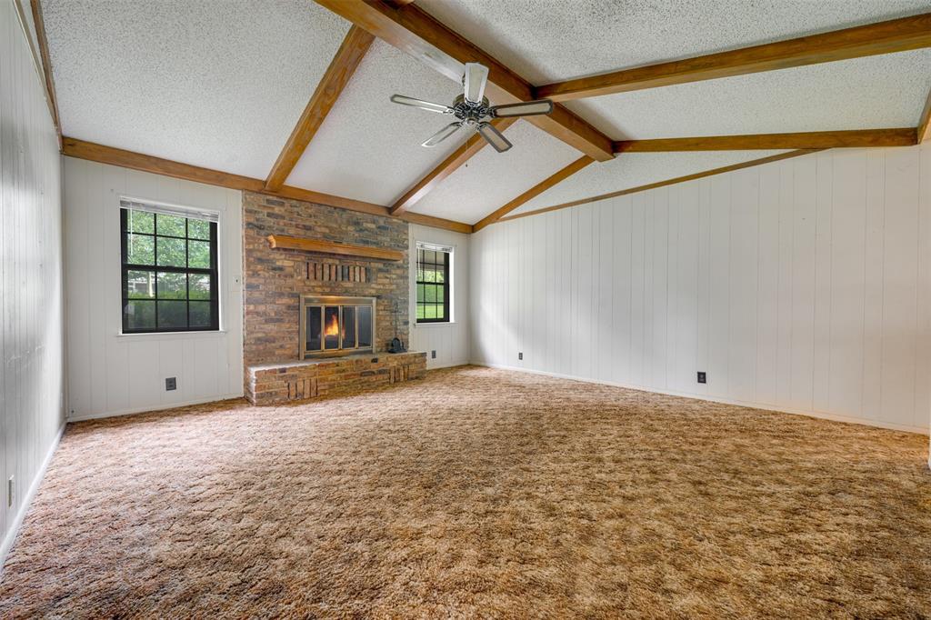 8798 Hill N Dale Road Tyler, TX 75709 - Photo 5 of 31 Spacious interior with vaulted ceilings, exposed wood beams, and a prominent brick fireplace with a wood mantle
