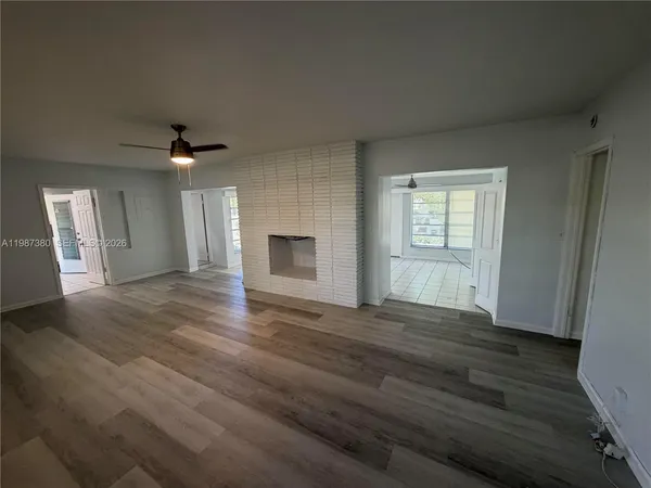 a view of an empty room with window and wooden floor