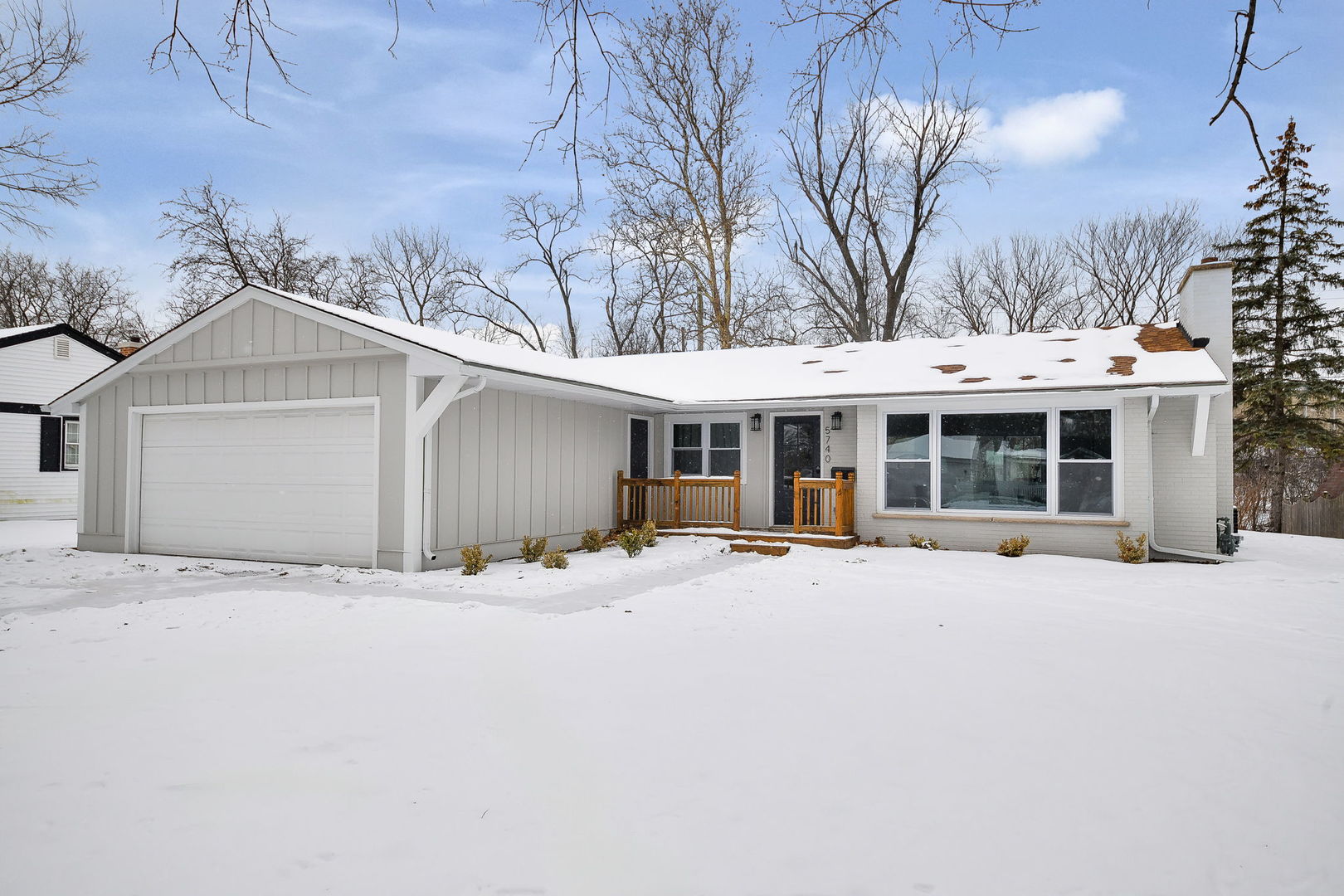 a front view of a house with a yard covered in snow