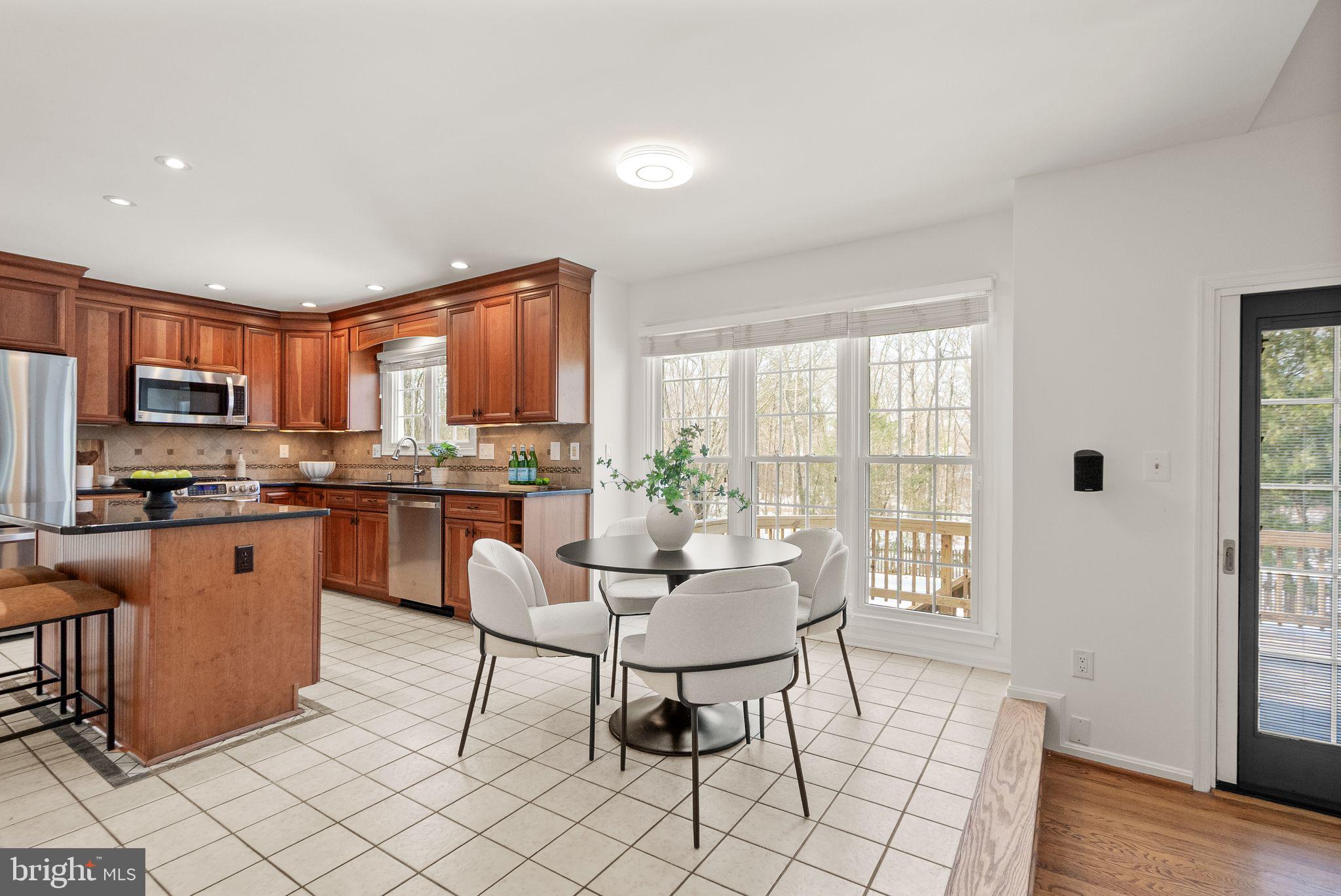 8144 Tall Timber Drive Gainesville, VA 20155 - Photo 24 of 73 a open kitchen with granite countertop a stove a sink a dining table and chairs