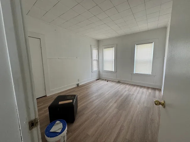 an empty room with wooden floor and natural light