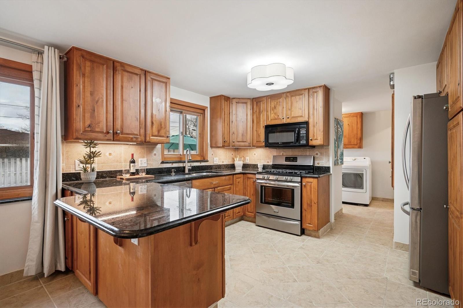 3880 Balsam Street Wheat Ridge, CO 80033 - Photo 18 of 40 a kitchen with granite countertop a refrigerator stove and oven