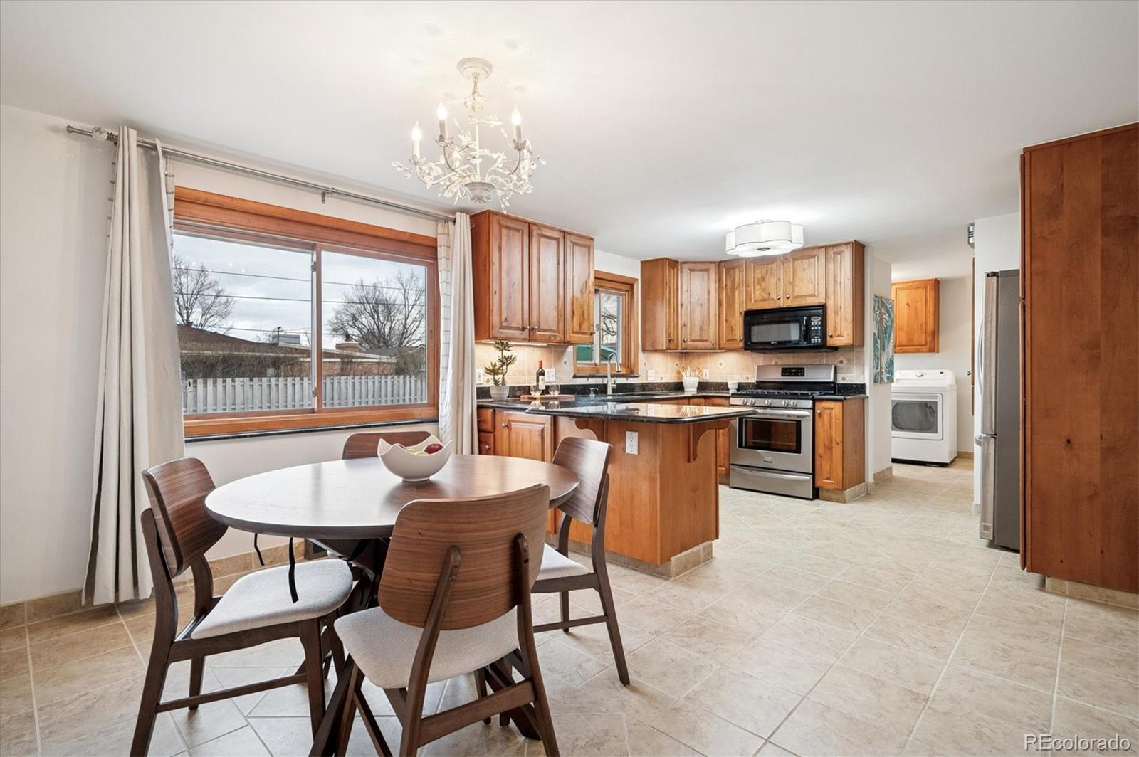 3880 Balsam Street Wheat Ridge, CO 80033 - Photo 5 of 40 a kitchen with stainless steel appliances granite countertop a stove a refrigerator a kitchen island a dining table and chairs
