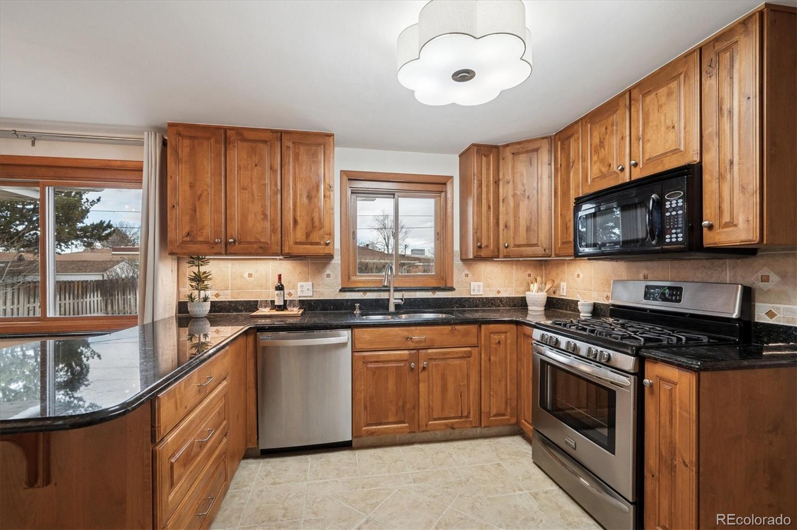 3880 Balsam Street Wheat Ridge, CO 80033 - Photo 7 of 40 a kitchen with stainless steel appliances granite countertop a stove sink microwave and window