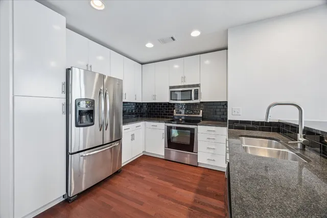 a kitchen with granite countertop white cabinets and stainless steel appliances