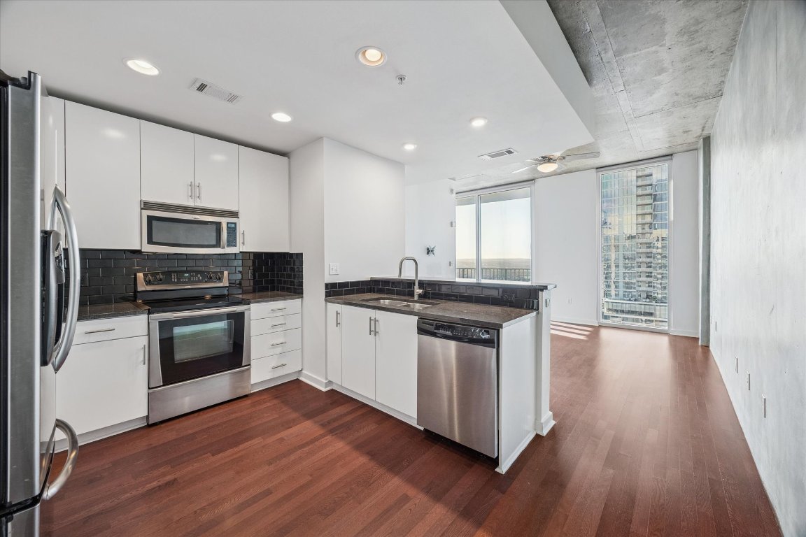 360 Nueces Street, Unit 4008 Austin, TX 78701 - Photo 4 of 40 a kitchen with granite countertop white cabinets and stainless steel appliances