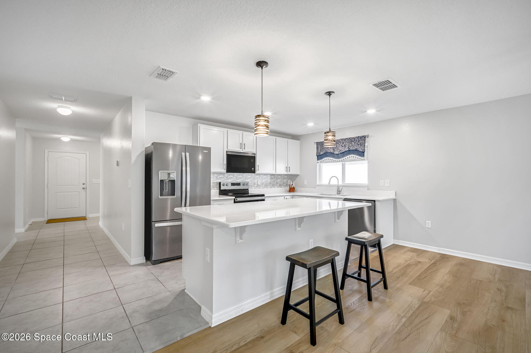 1219 Moscato Drive Titusville, FL 32780 - Photo 4 of 21 a kitchen with stainless steel appliances kitchen island a table chairs in it and wooden floors