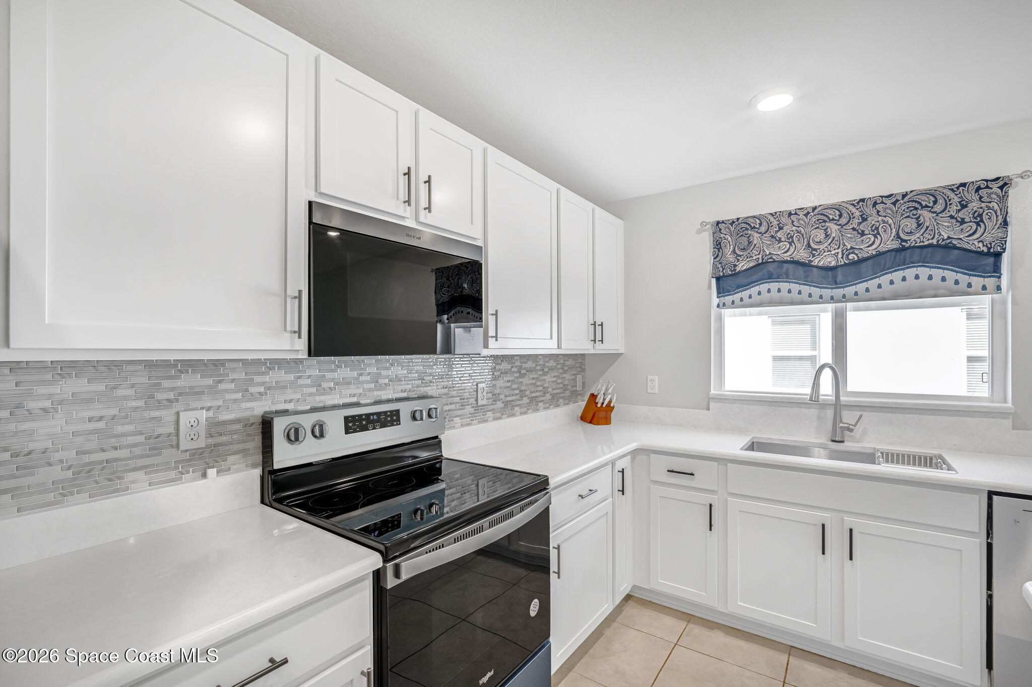 1219 Moscato Drive Titusville, FL 32780 - Photo 5 of 21 a kitchen with sink a microwave a stove and cabinets