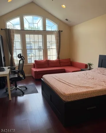 a bedroom with a bed a table and large windows